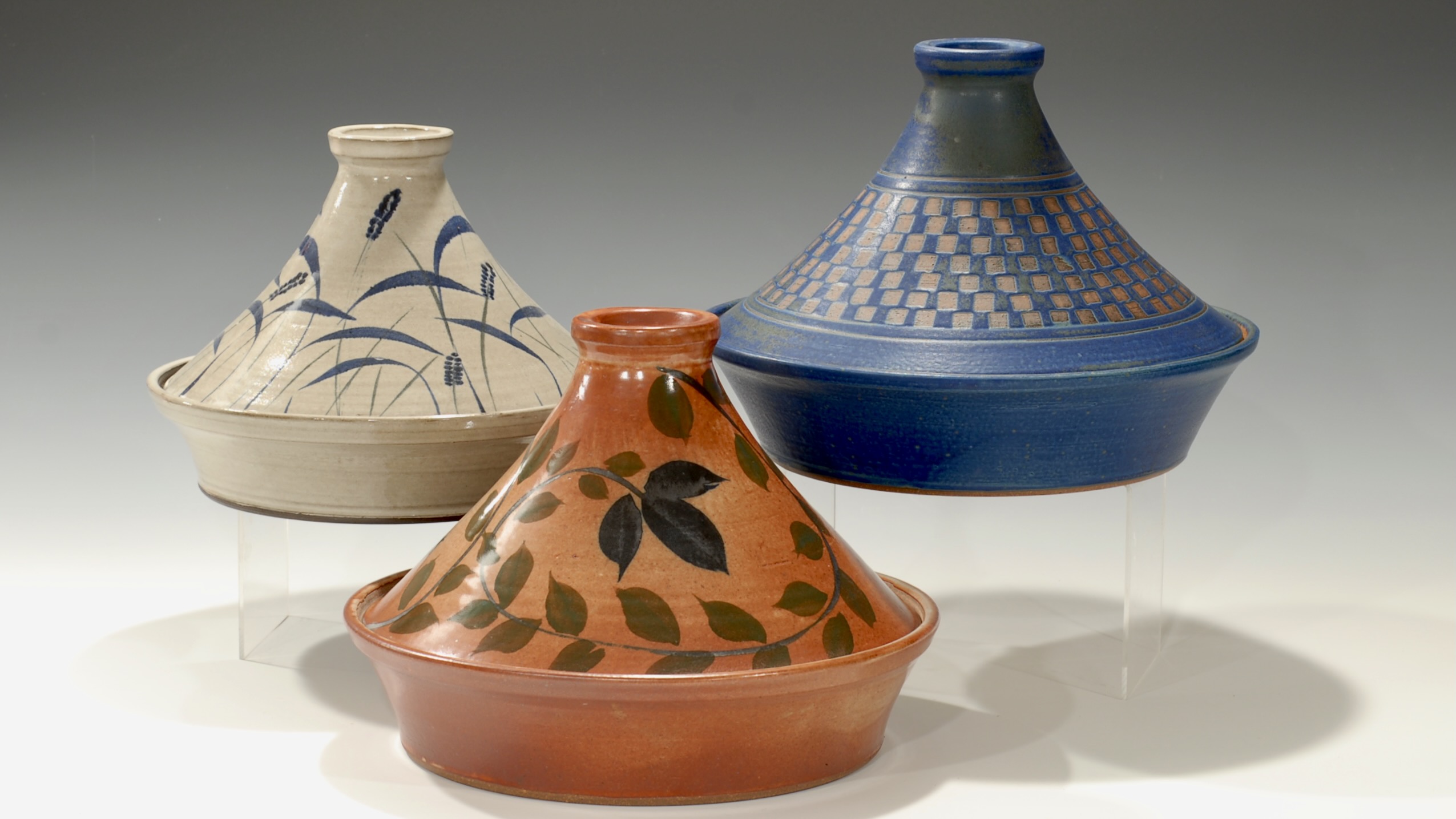 Three ceramic vessels with wide, conical shapes and decorative patterns, displayed against a neutral background.