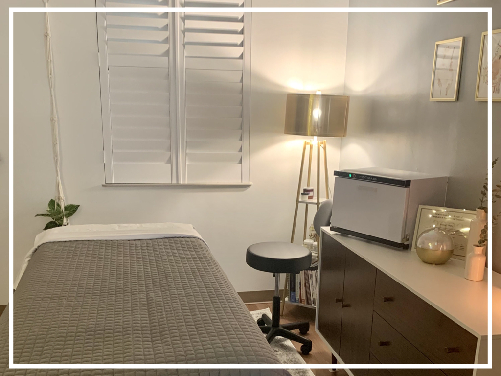 Bedroom with bed, window with shutters, lamp, desk, and chair, in neutral tones.