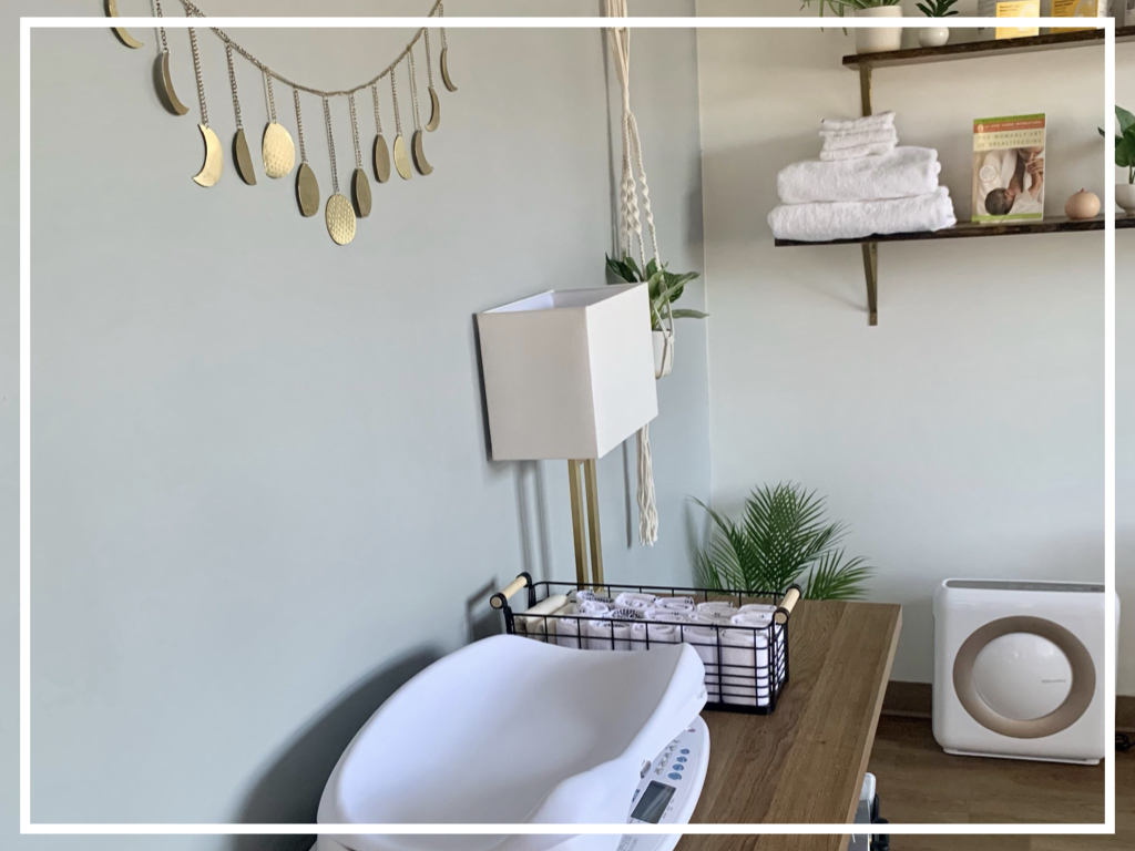 Bathroom with a bathtub, wall shelves with towels, and decorative wall hanging, against a light-colored wall.