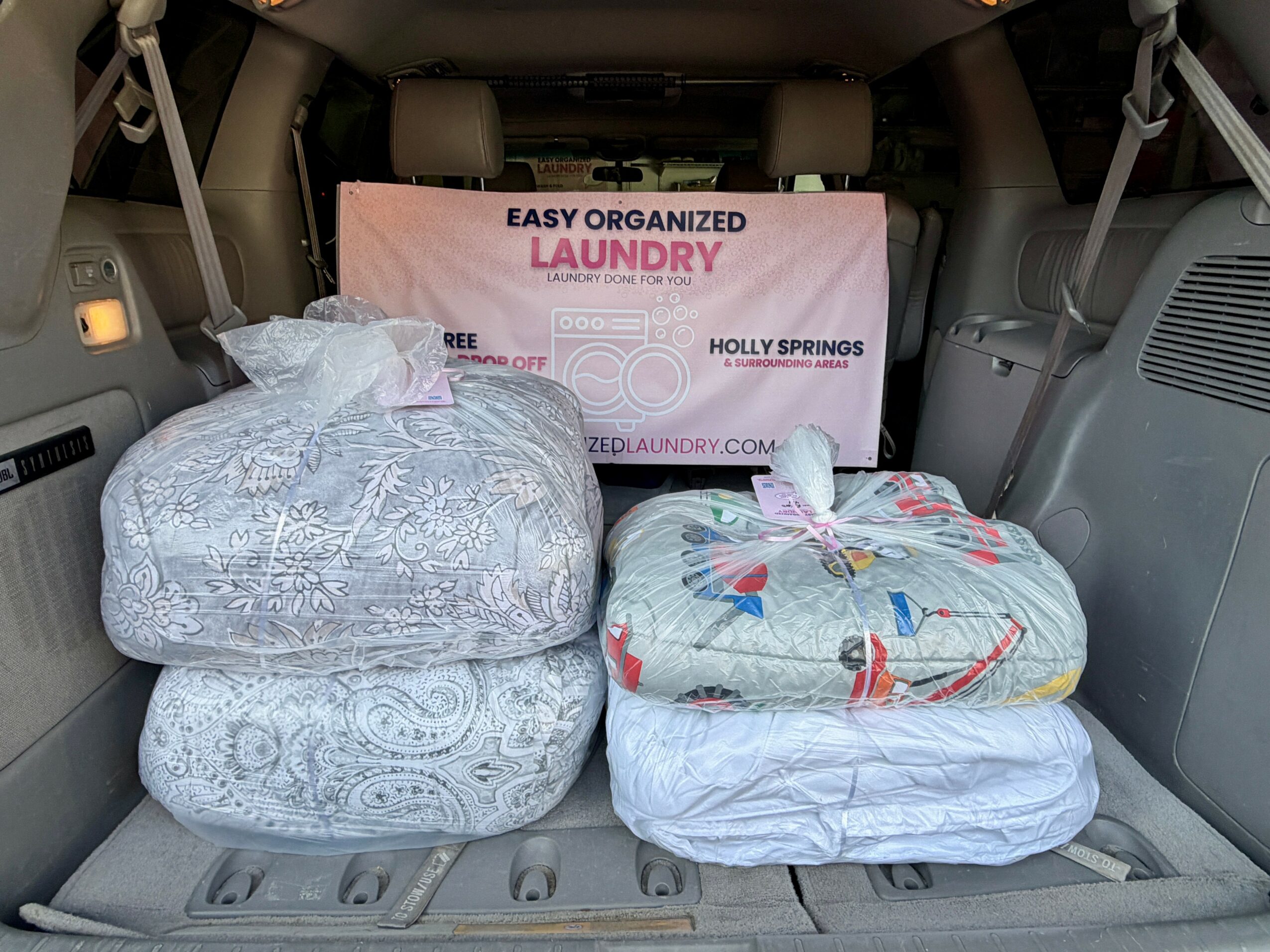 The trunk contains four laundry bags and a pink laundry box with text, with the bags stacked and the box at the back.