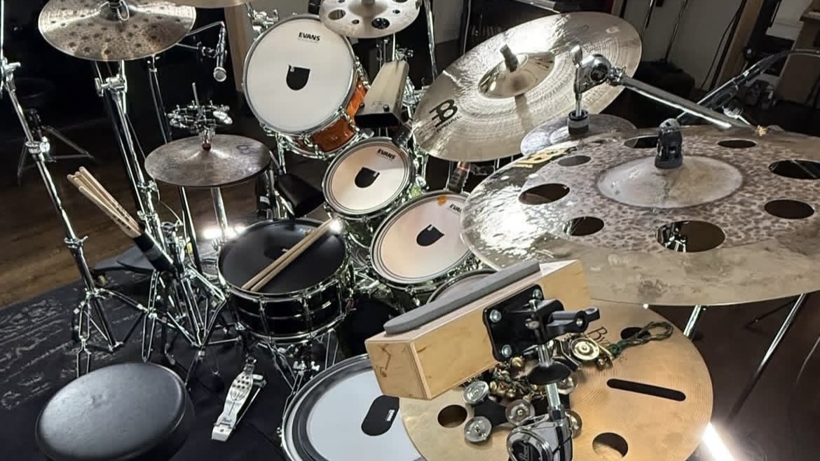 A drum set with cymbals, drums, and percussion instruments arranged on a stage or studio floor.
