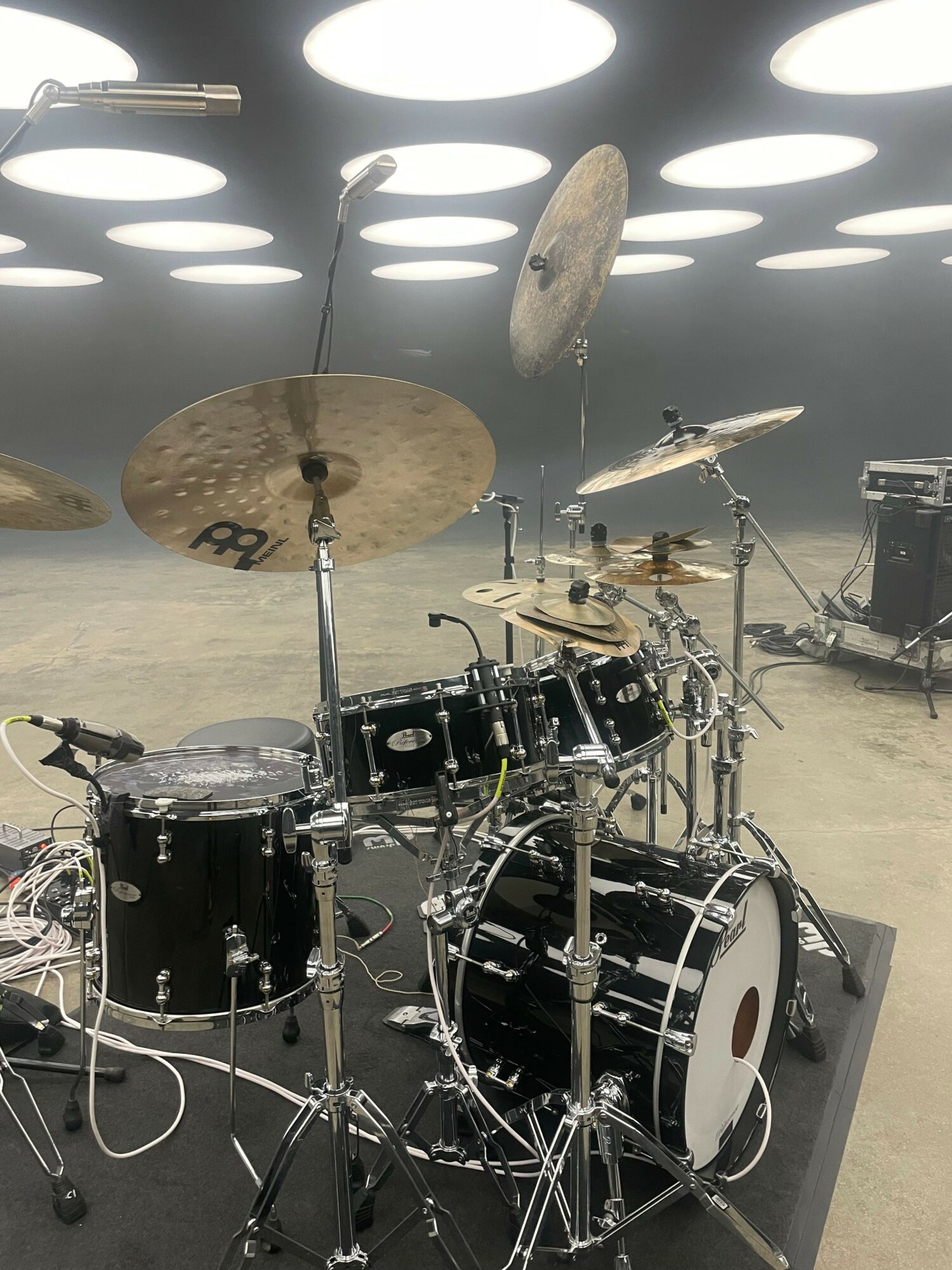 A drum set with cymbals and drums on a stage with circular light patterns on the wall behind.