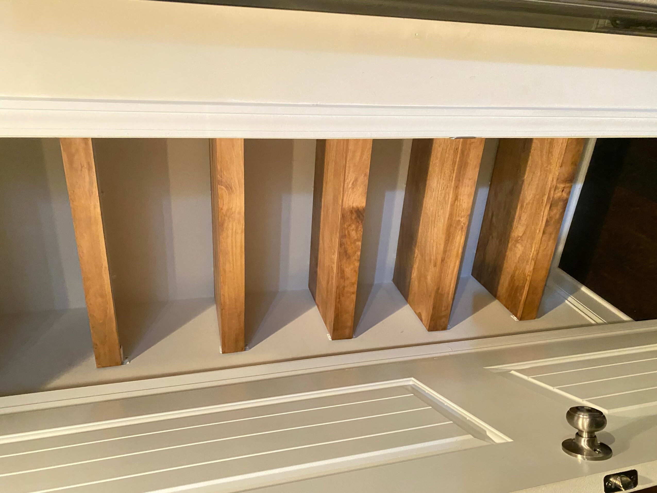 View of wooden slats inside a white frame, seen from below, with a metal latch on the right side.
