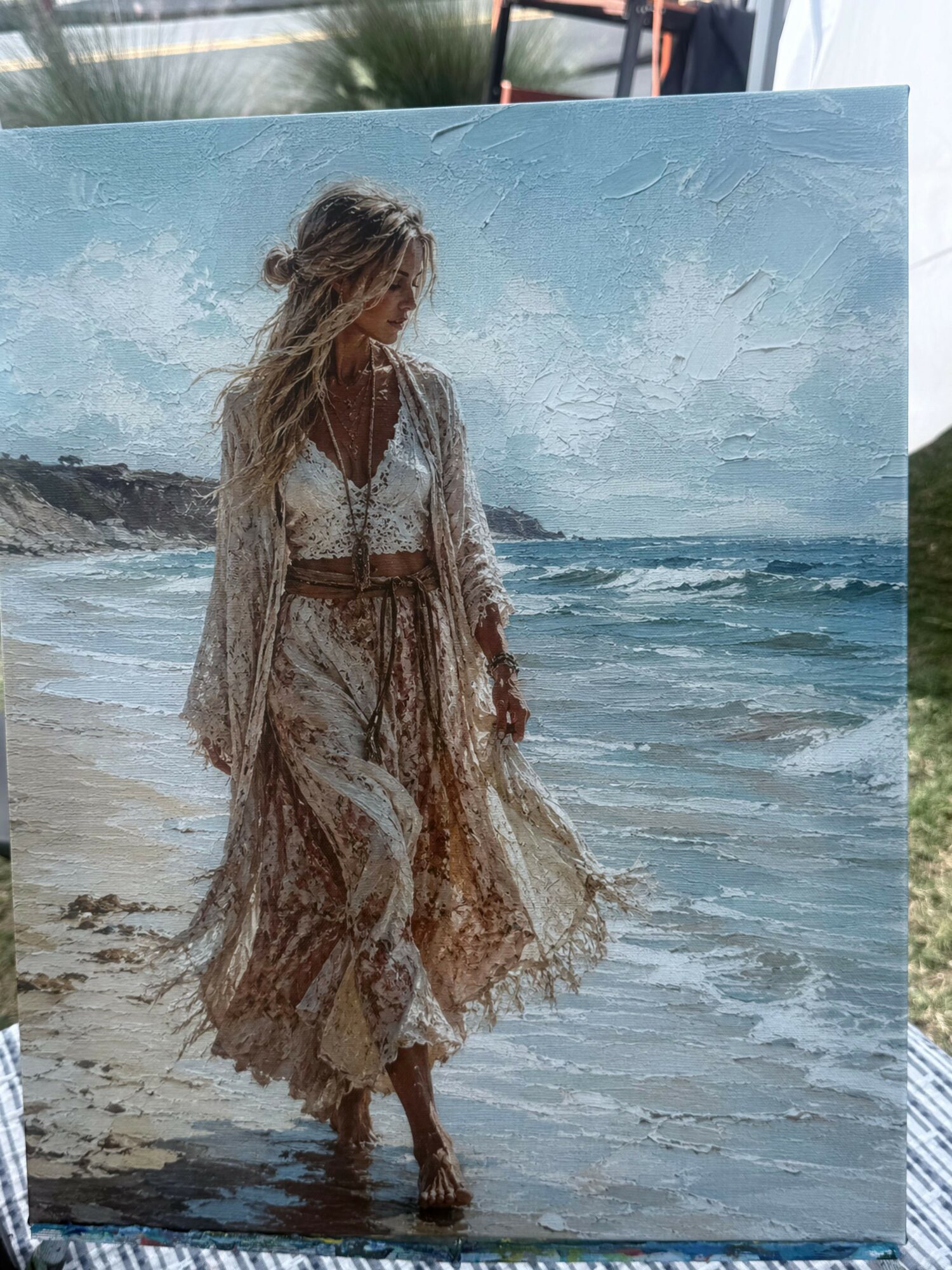 Person in a flowing dress standing on a beach with waves and sky in the background.