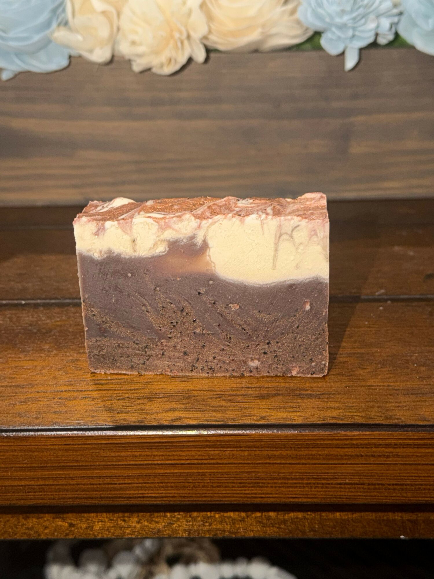 A rectangular brick with a mix of red, brown, and beige colors on a wooden surface.