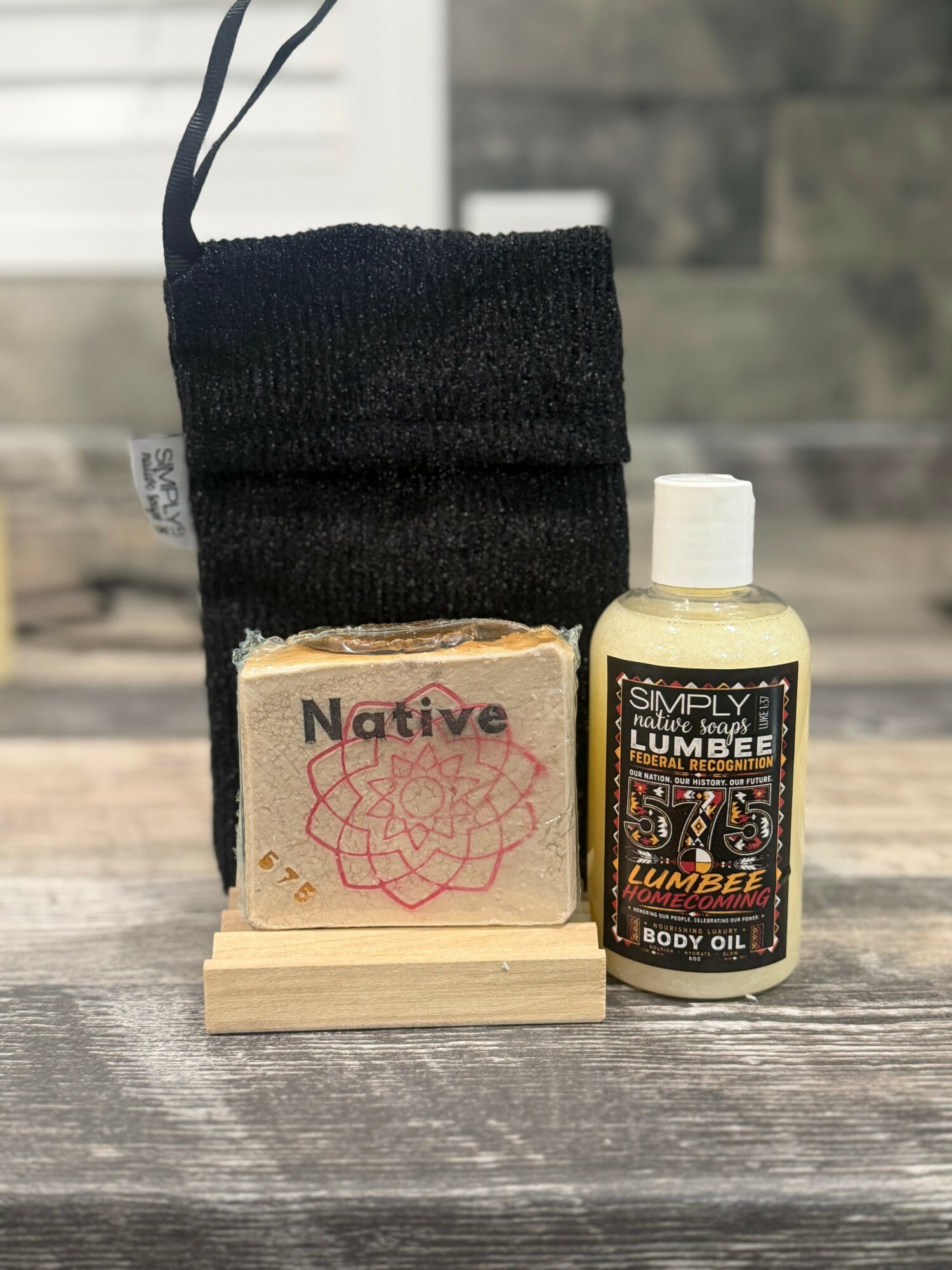 Black fabric pouch, bar of soap labeled 'Native,' and a bottle of body oil on a wooden surface.