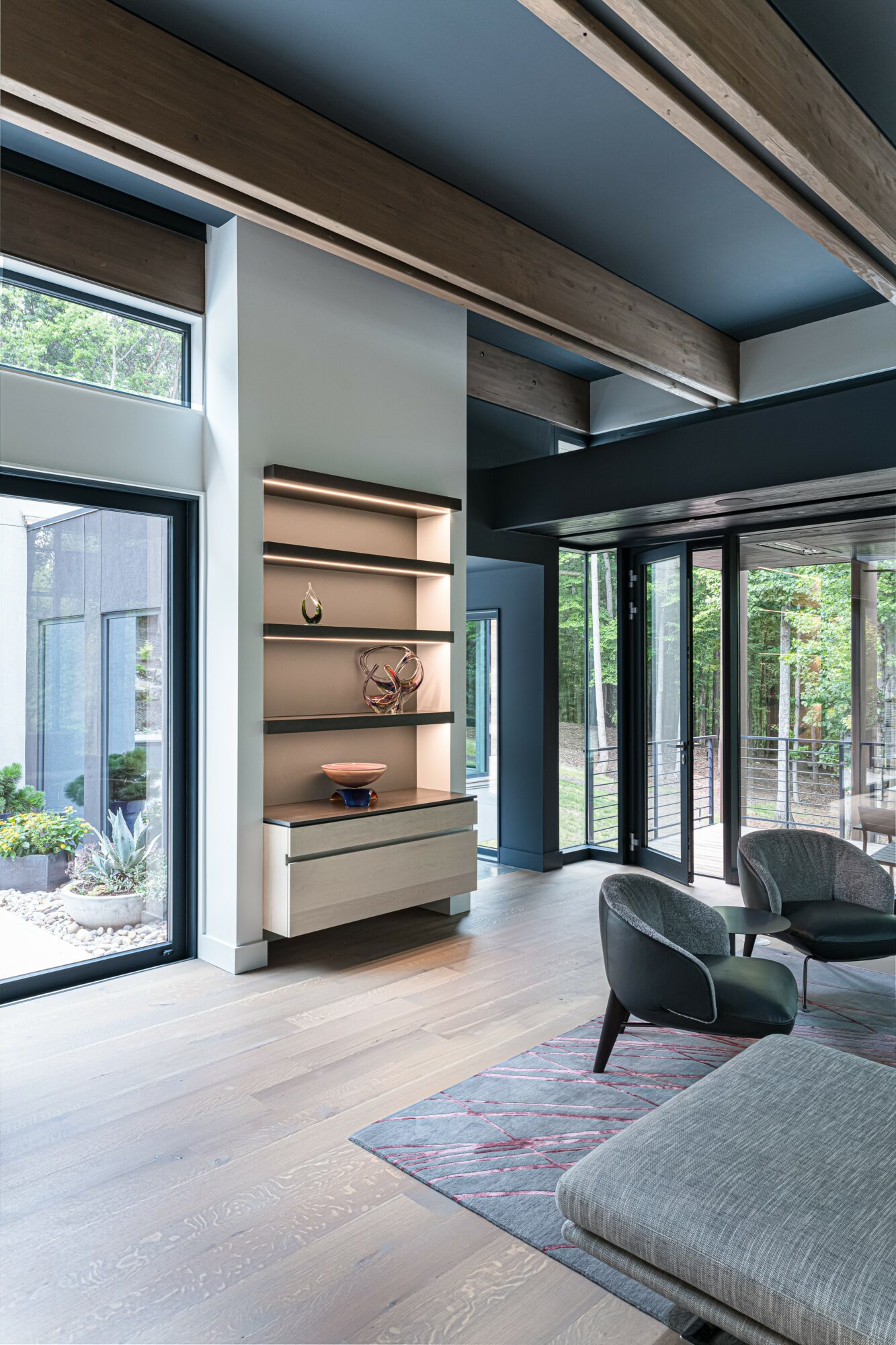 Interior space with large windows, a built-in bookshelf, and seating area, featuring modern decor and natural light.