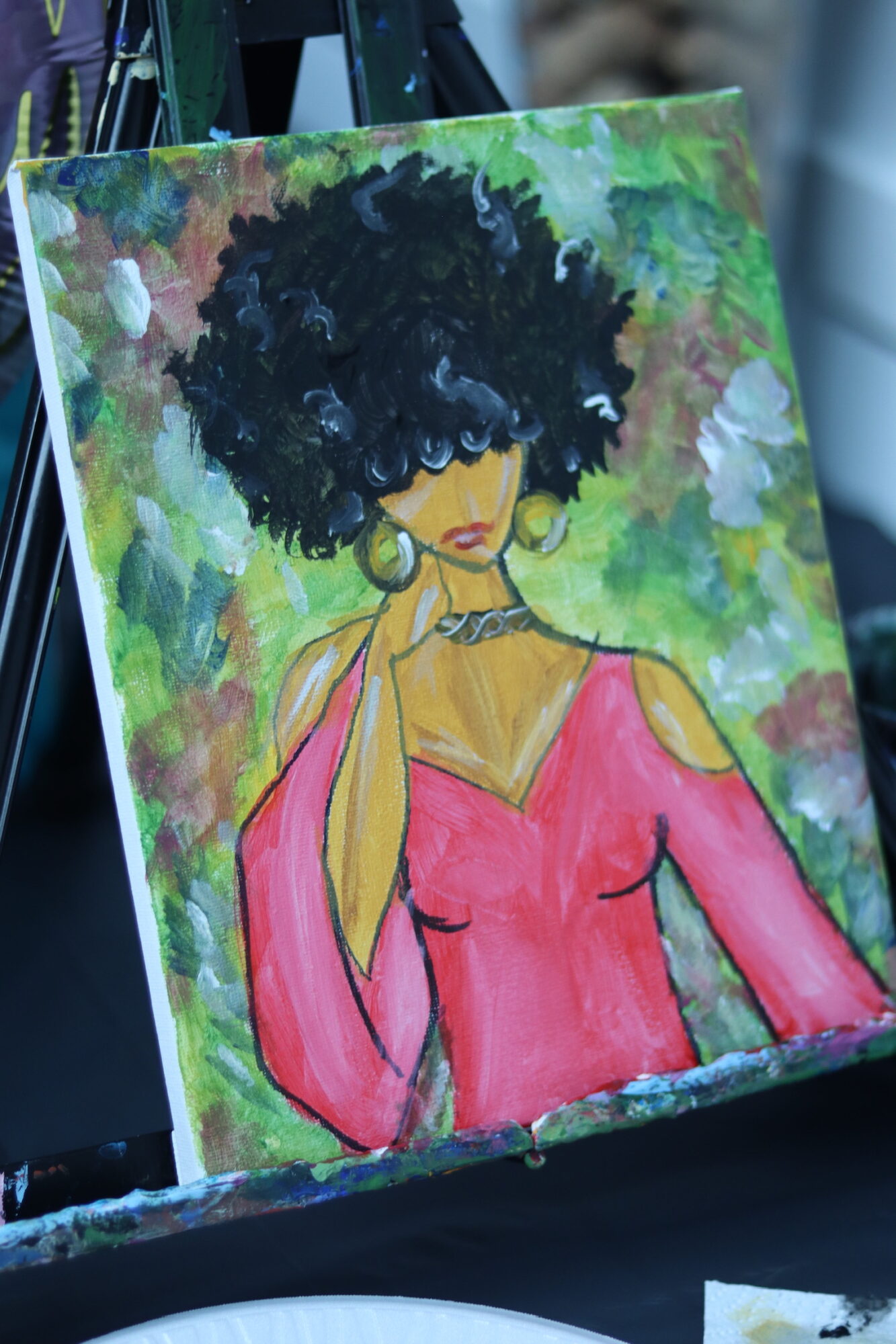 Painting of a woman with curly hair wearing a pink off-shoulder top and large earrings, with a colorful background.