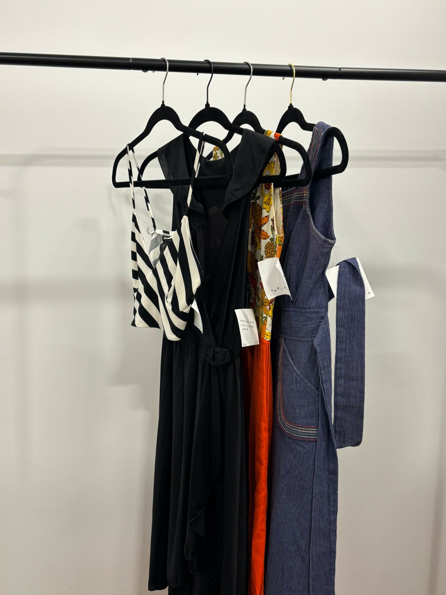 Stack of folded jeans and clothing on a white shelf, with black and white striped fabric visible.
