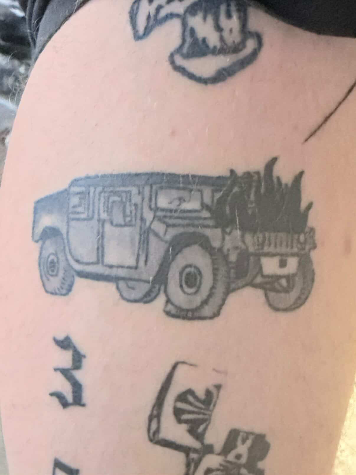 Tattoo of a vehicle with a fire on the back, and some symbols or characters below it.