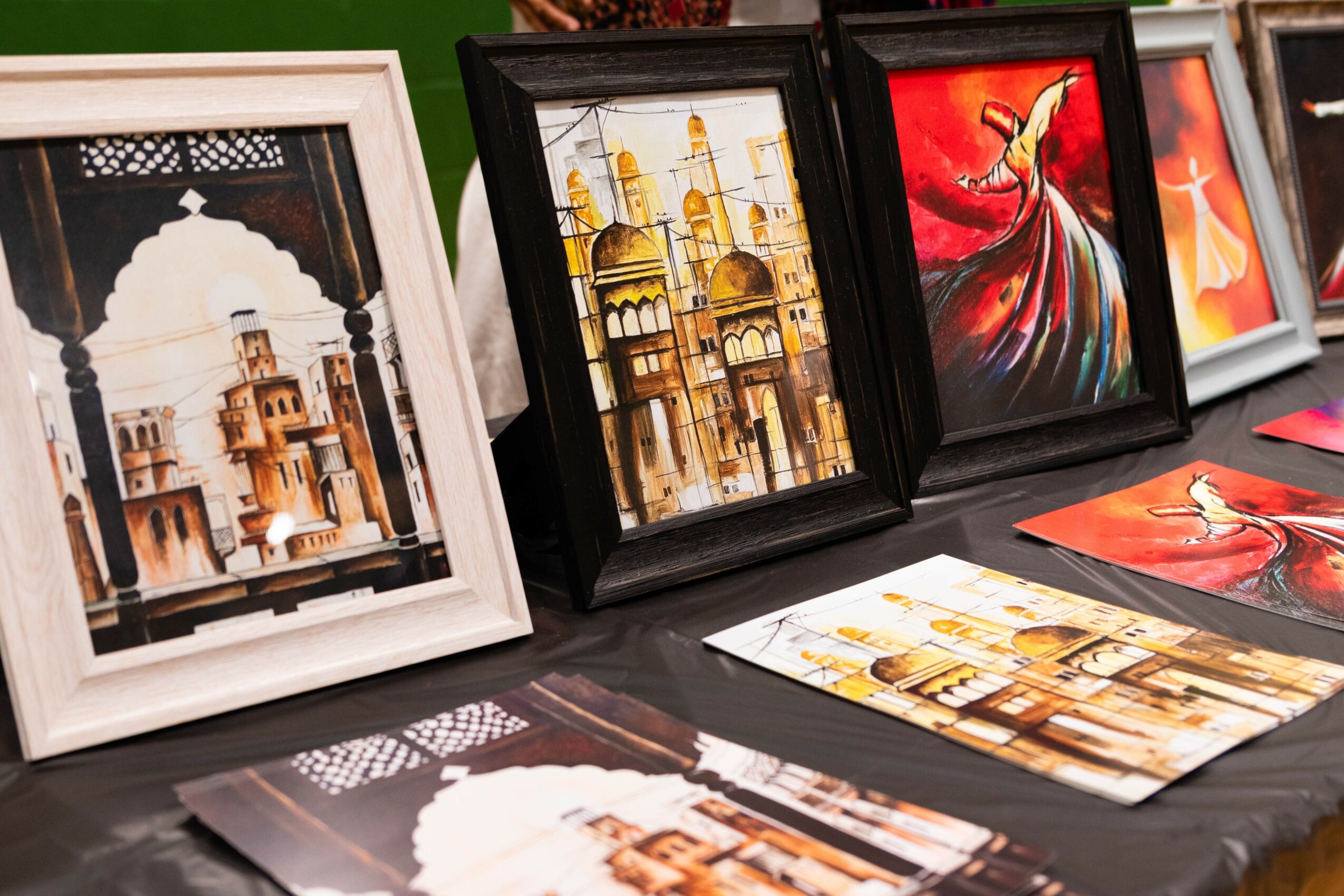 Collection of framed artwork and printed images on a table, featuring architectural and dance-themed images.