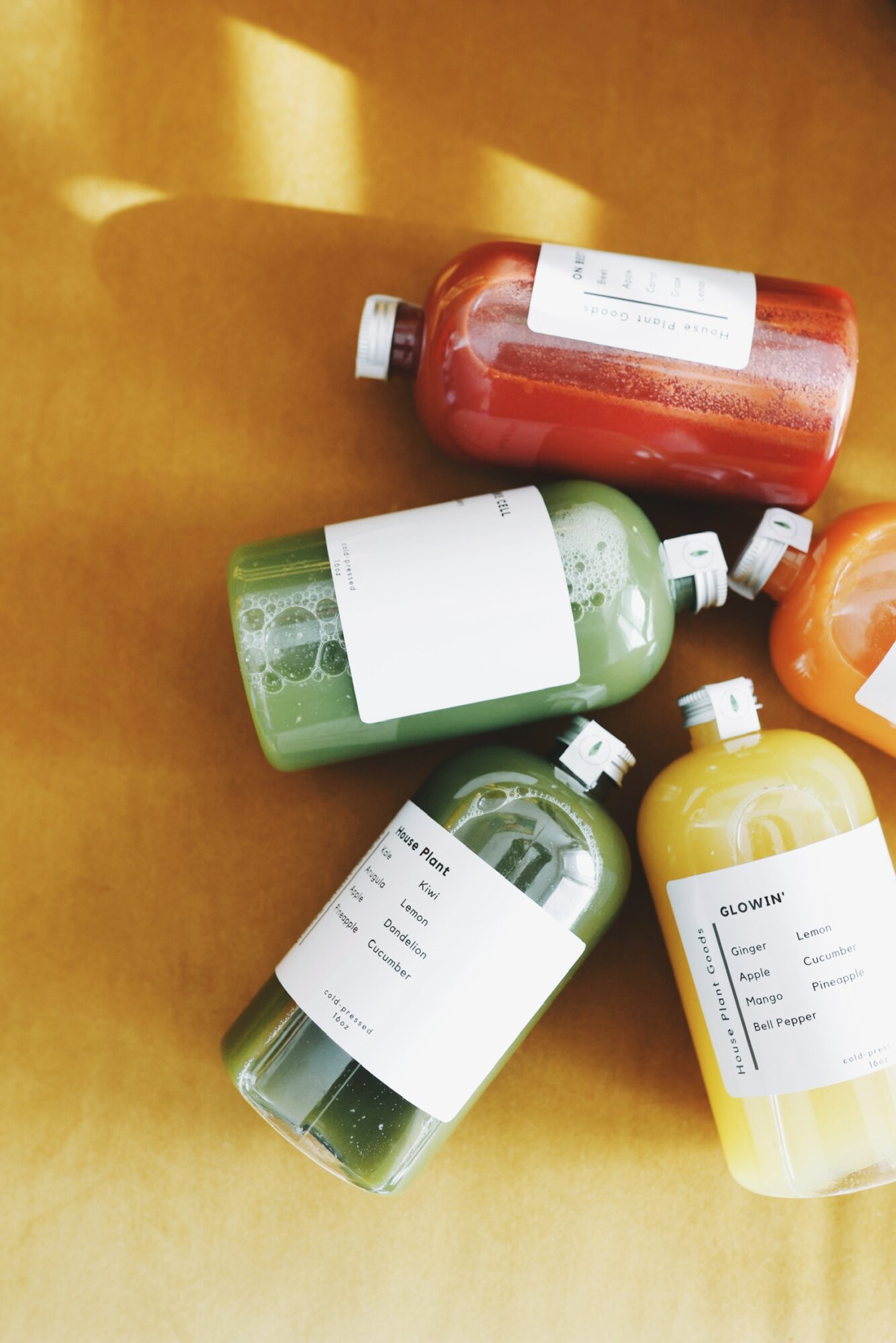 Four bottles of different colors and sizes on a wooden surface, with labels and caps visible.