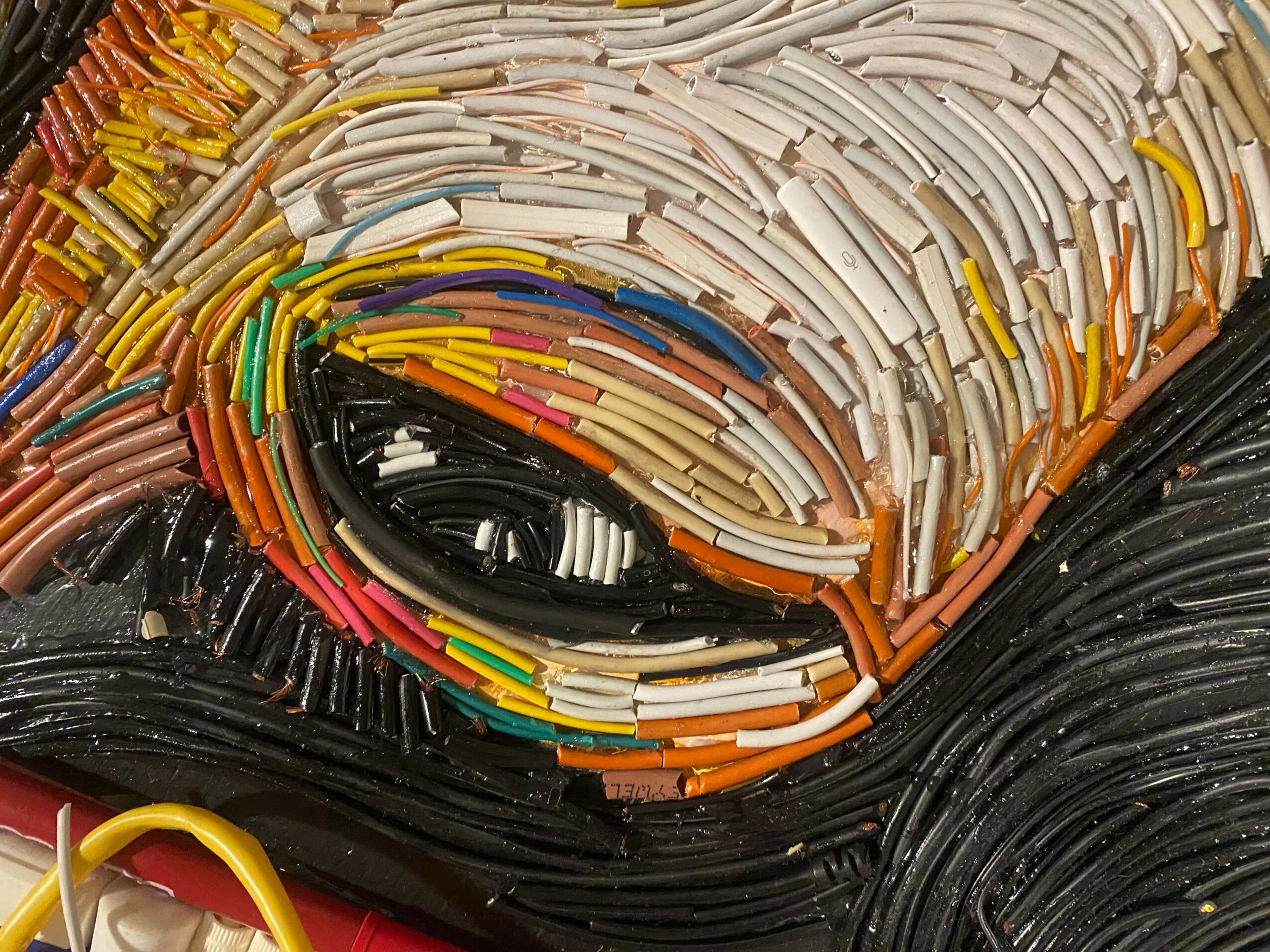Close-up of colorful cables and wires arranged in a pattern, with black, white, yellow, and other colors visible.