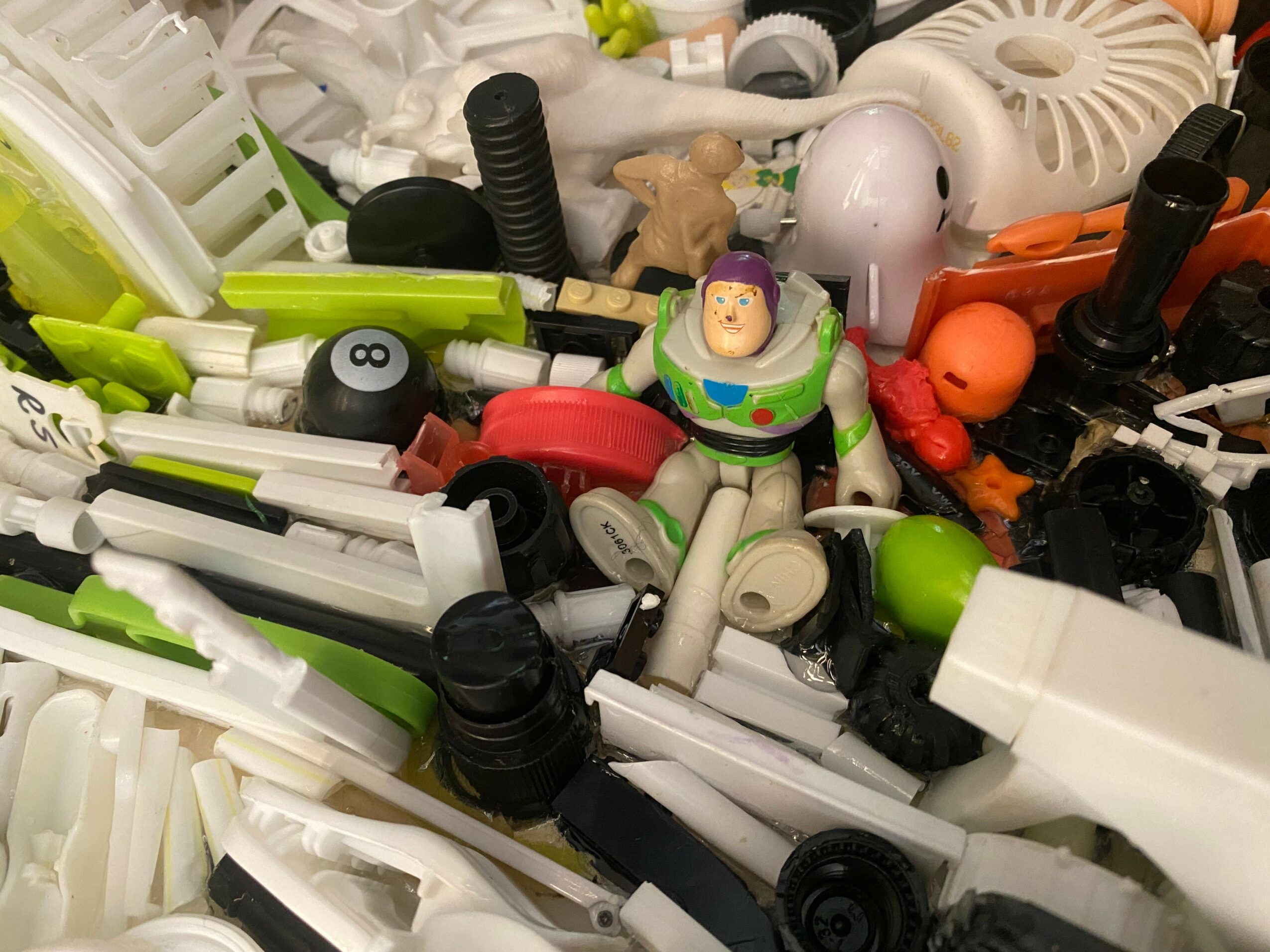 A pile of various pens, markers, and toys, including a Buzz Lightyear figure, scattered randomly.