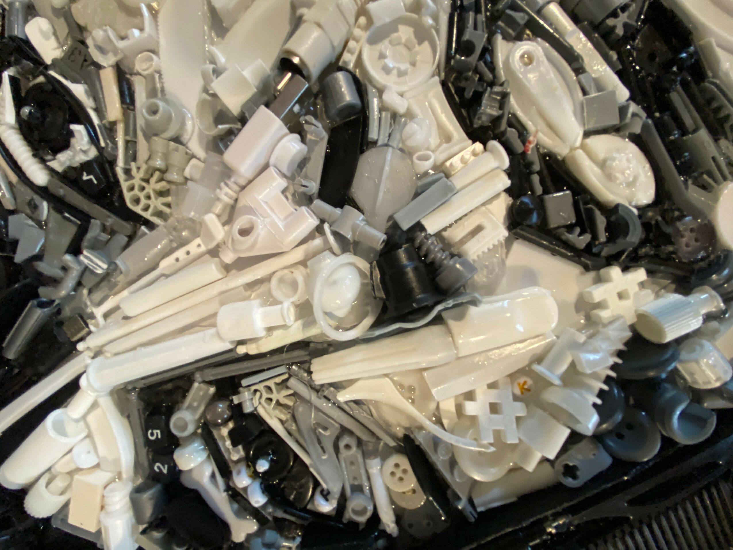 A pile of various black and white plastic mechanical parts and components.
