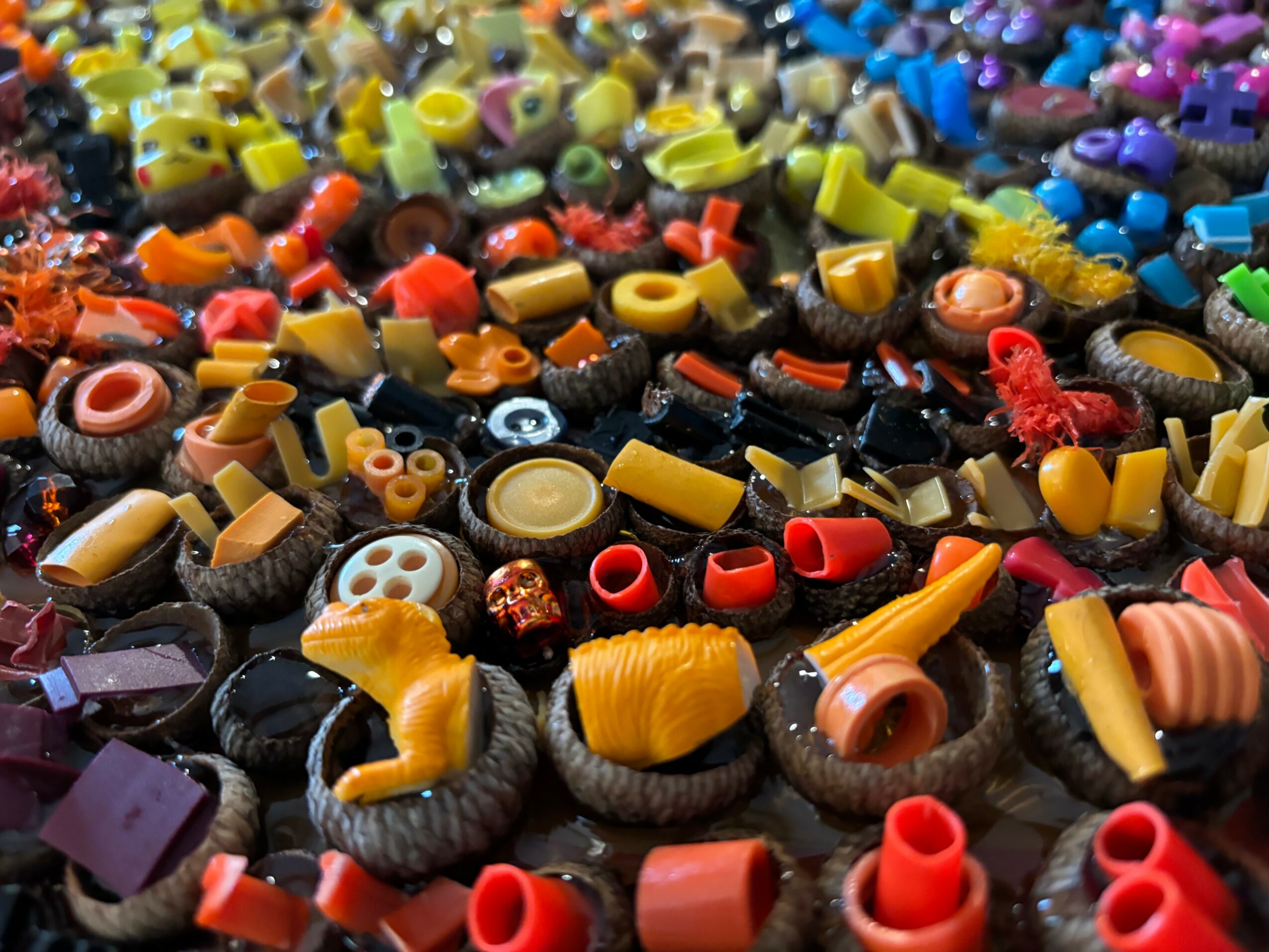 Close-up of colorful plastic and rubber toy parts, including wheels, tubes, and small objects, scattered randomly.