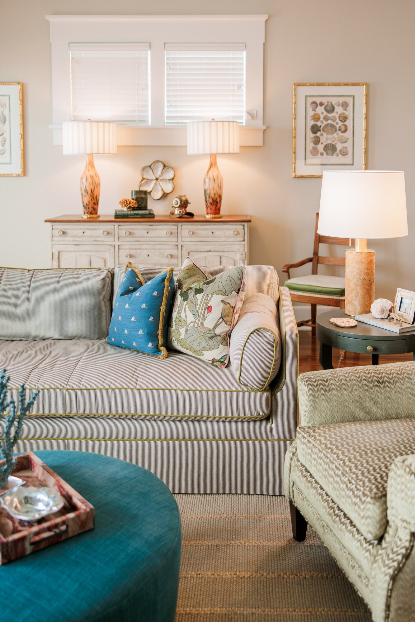 Living room with a striped sofa, decorative pillows, a side table with a lamp, and framed artwork on the wall.