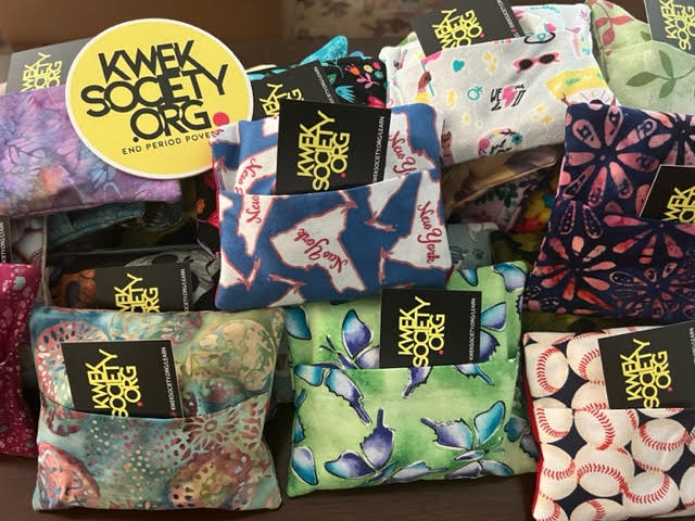 Multiple colorful fabric pouches with black tags displaying yellow text, arranged in a pile.