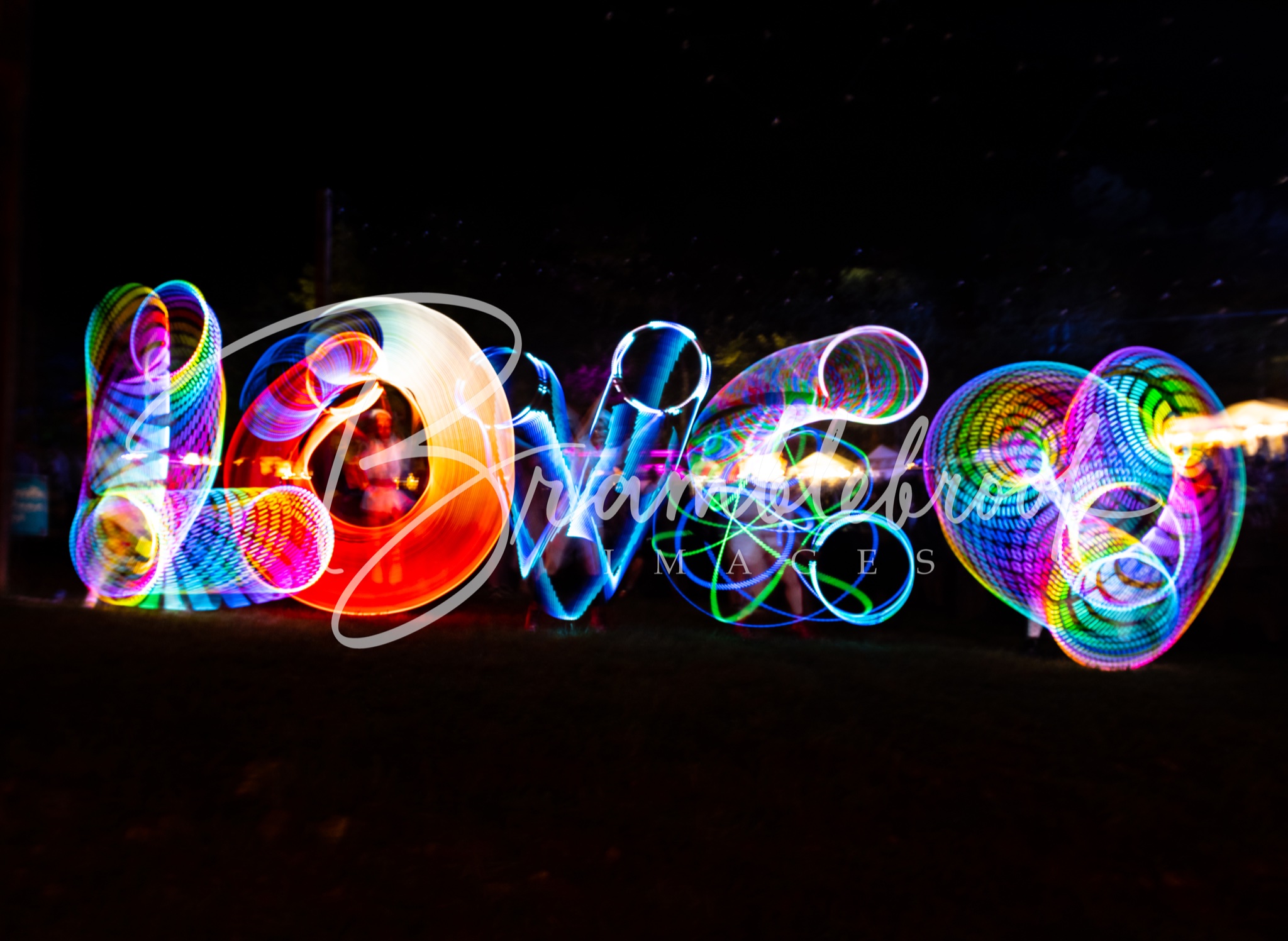 Colorful light trails form the word 'LOVE' against a dark background, with vibrant, swirling patterns and bright colors.