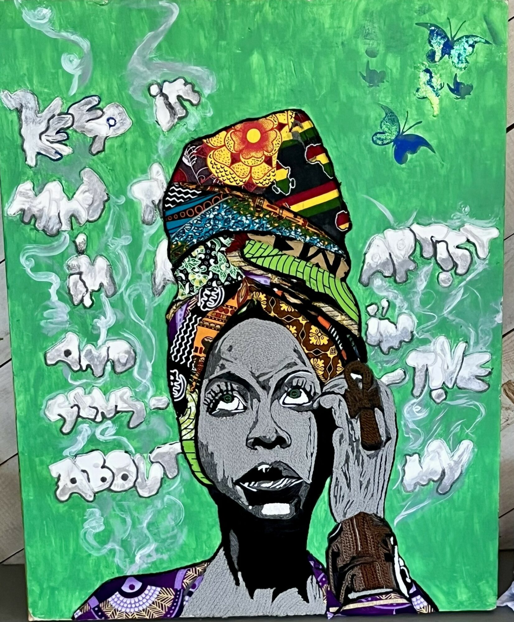 Portrait of a woman with a colorful headwrap, gray skin, and expressive eyes, set against a green background with white animals and blue butterflies.