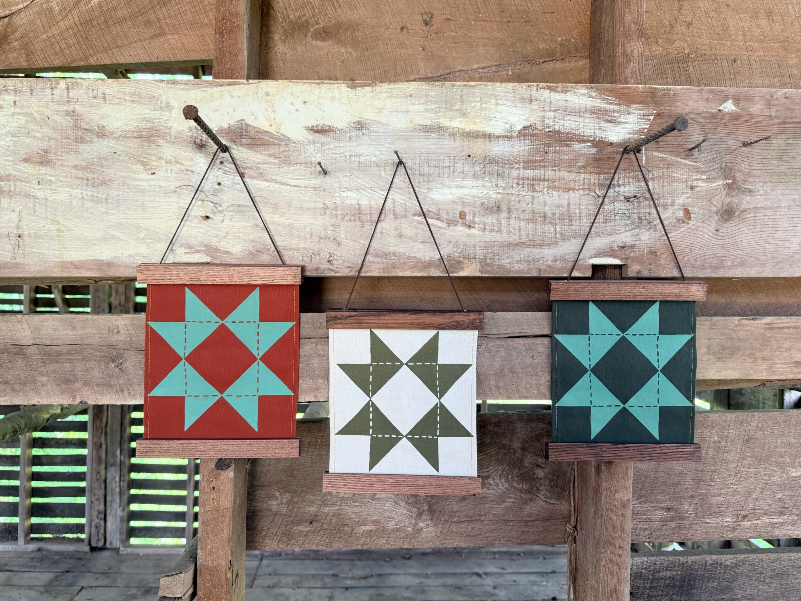 Three hanging decorative lanterns with geometric patterns, against a wooden background.