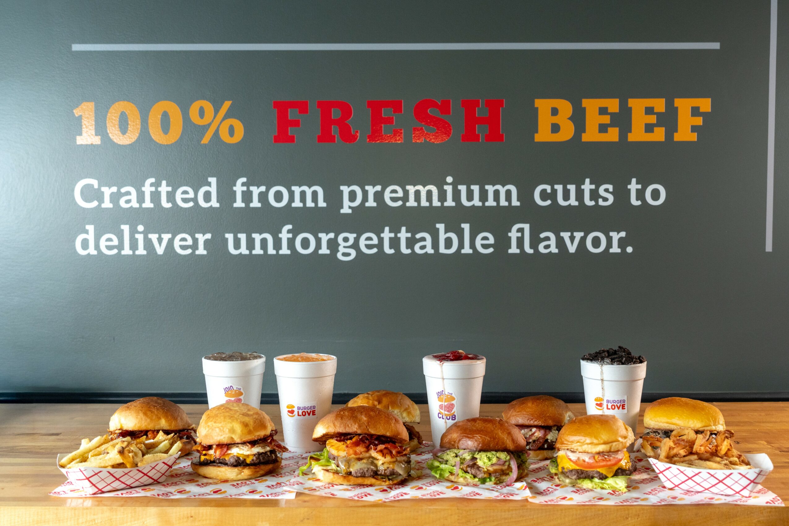 Sign advertising fresh beef with sandwiches and drinks on a counter, text highlights freshness and flavor.