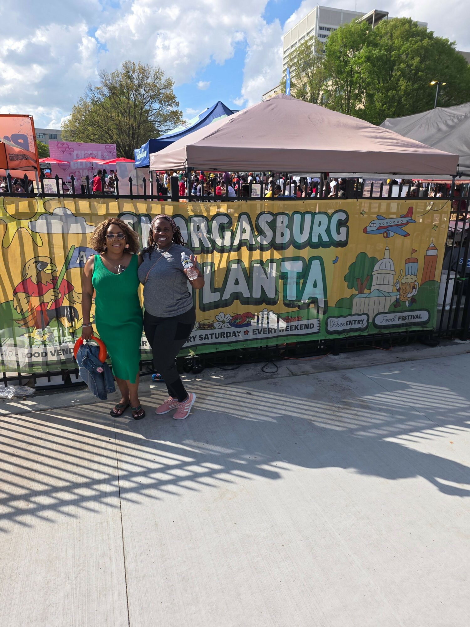 Two children stand in front of a colorful carnival game booth with a sign reading 'GROSBURG PLANT.'