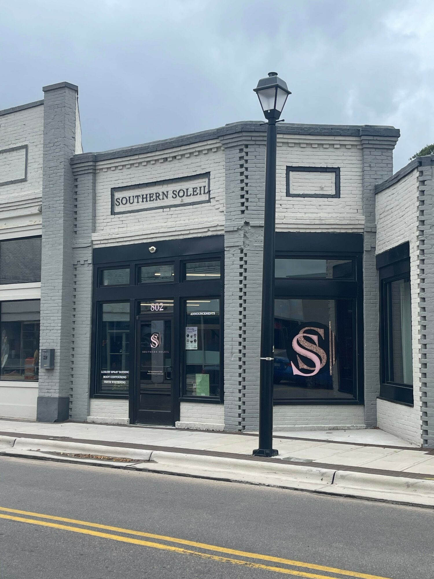 Street view of a building with a sign reading 'DOWNTOWN LOFTS' and a black door, sidewalk, and street lamp.