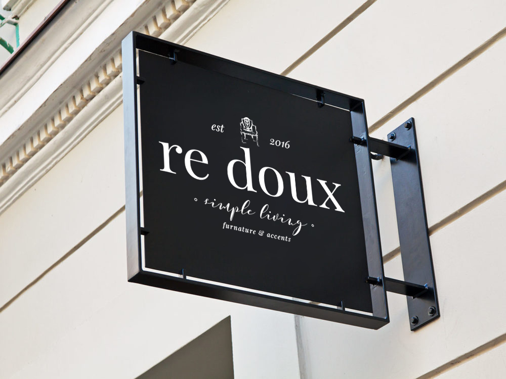 Black square sign with white text reading 're doux' and smaller text below, mounted on a wall.