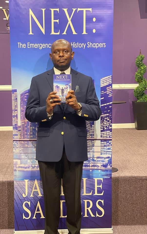 Man in suit holding a book in front of a purple backdrop with text about emergency history shapers.