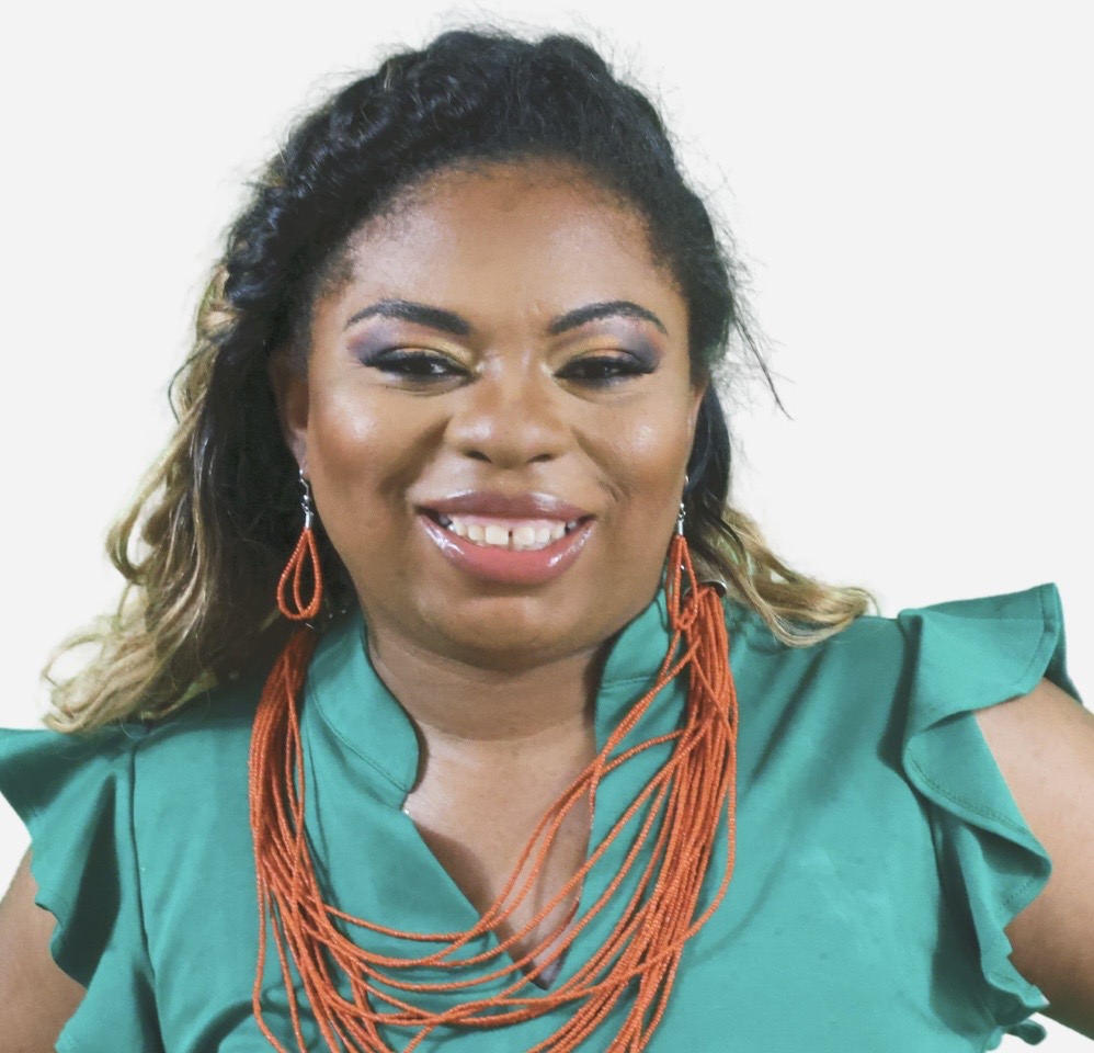 Woman with dark hair, wearing a teal top and orange jewelry, smiling at the camera.