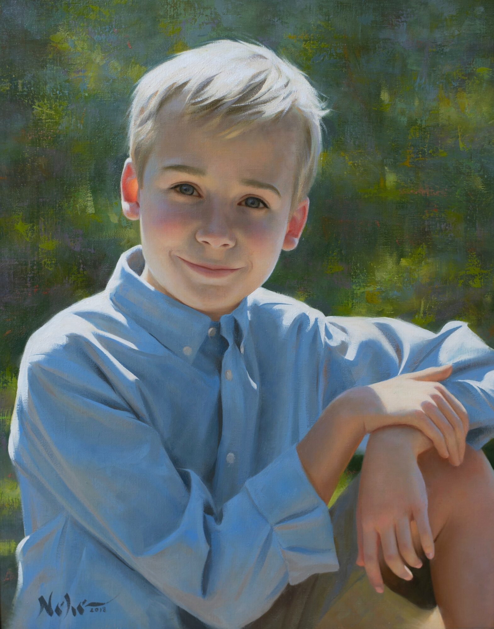Young boy with light hair wearing a blue shirt, smiling outdoors with a blurred green background.