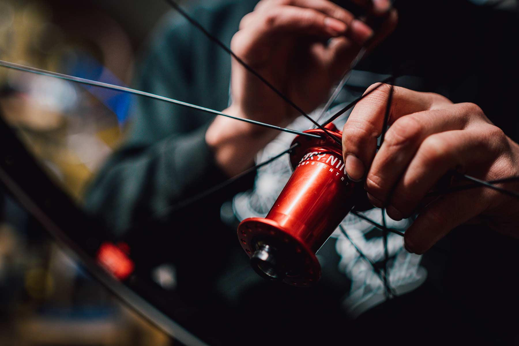 Person holding a red spool of thread and sewing needle, reflected in a mirror, with hands close-up.