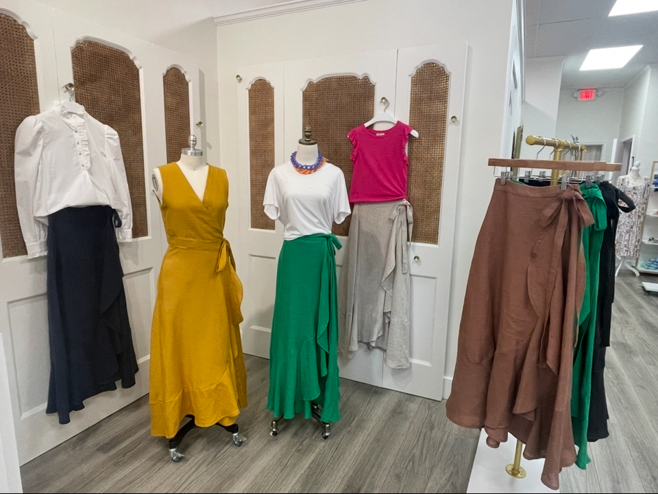 Display of mannequins dressed in colorful outfits and a clothing rack with brown and green garments in a store.