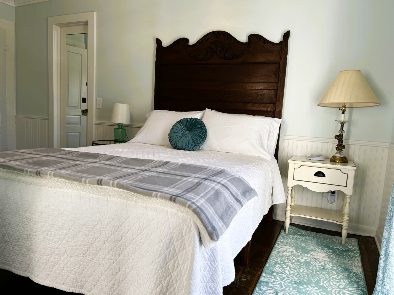 Bedroom with a large bed, dark wooden headboard, white bedding, and two bedside tables with lamps.