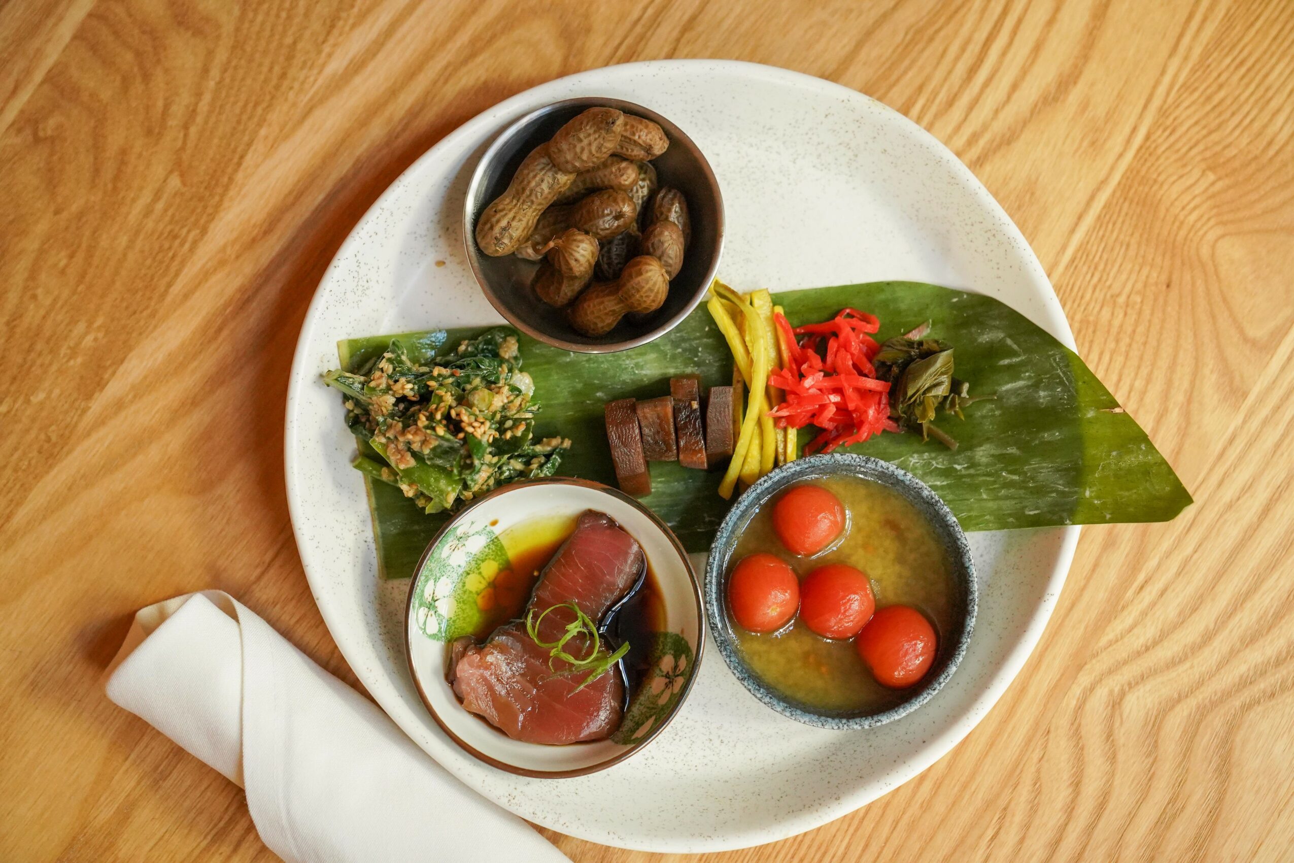 Plate with various foods including beans, vegetables, and tomatoes on a wooden table.