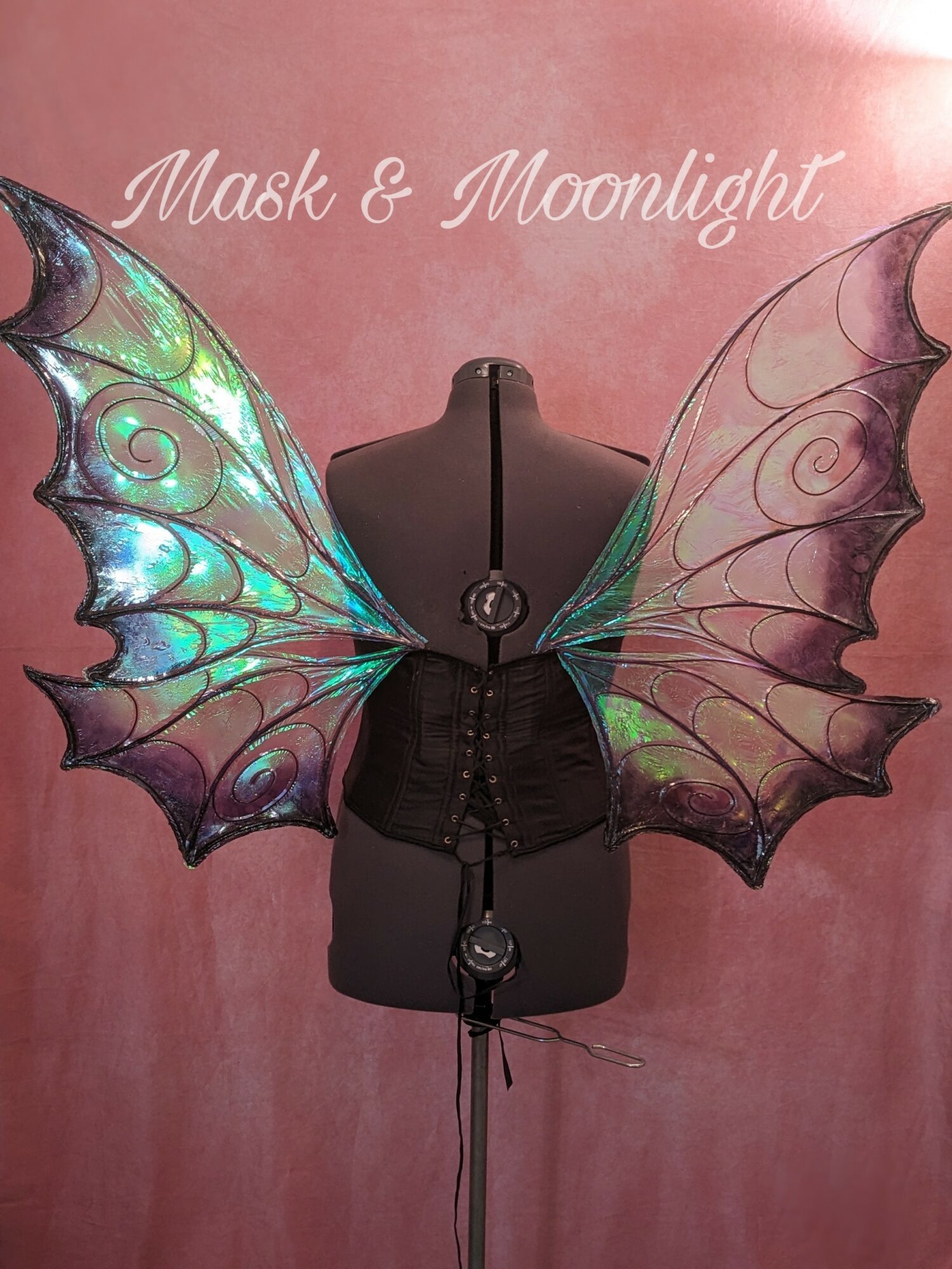 Black mannequin with iridescent butterfly wings against pink background, text reads 'Mask & Moonlight'.