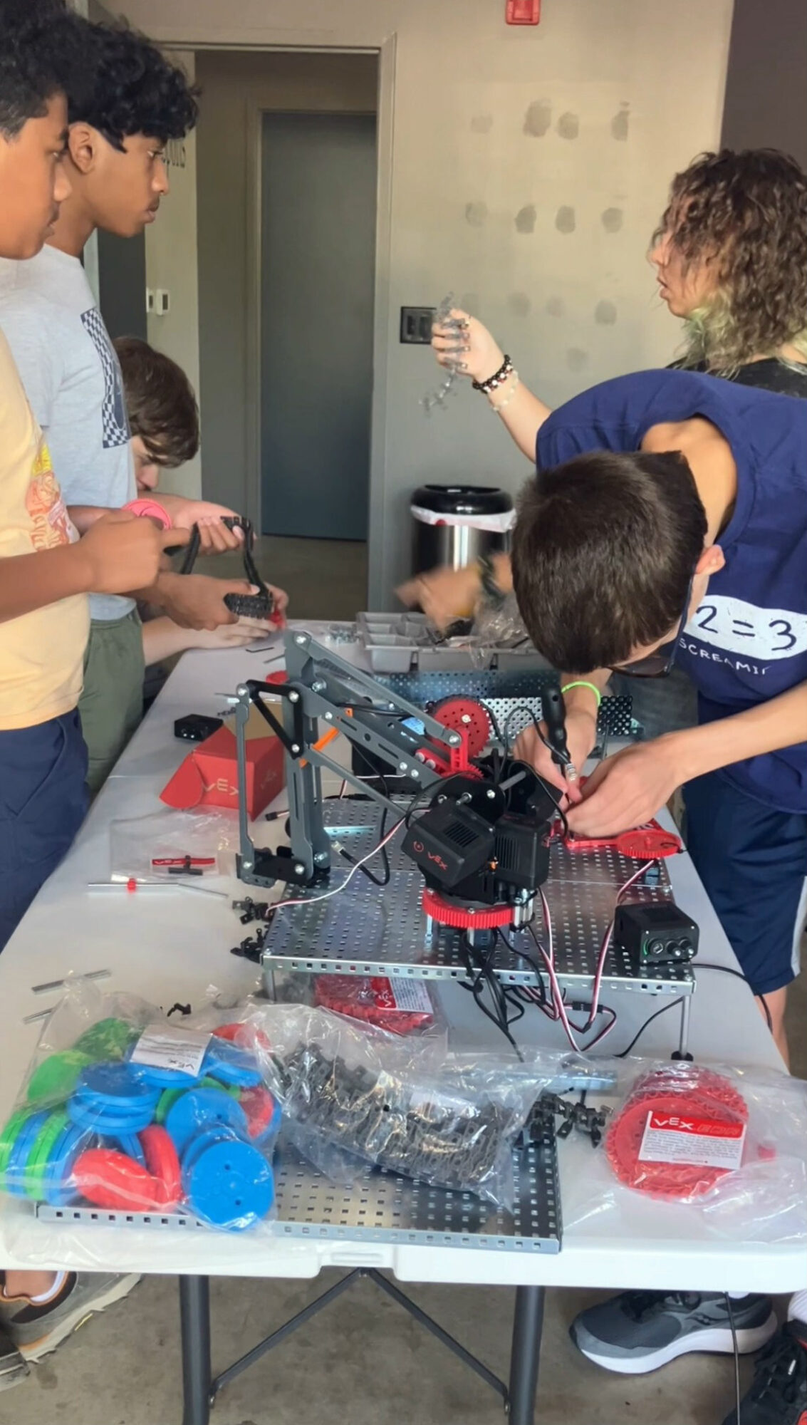 Group of children gathered around a table with a robotic project, working together on a science activity in a classroom.