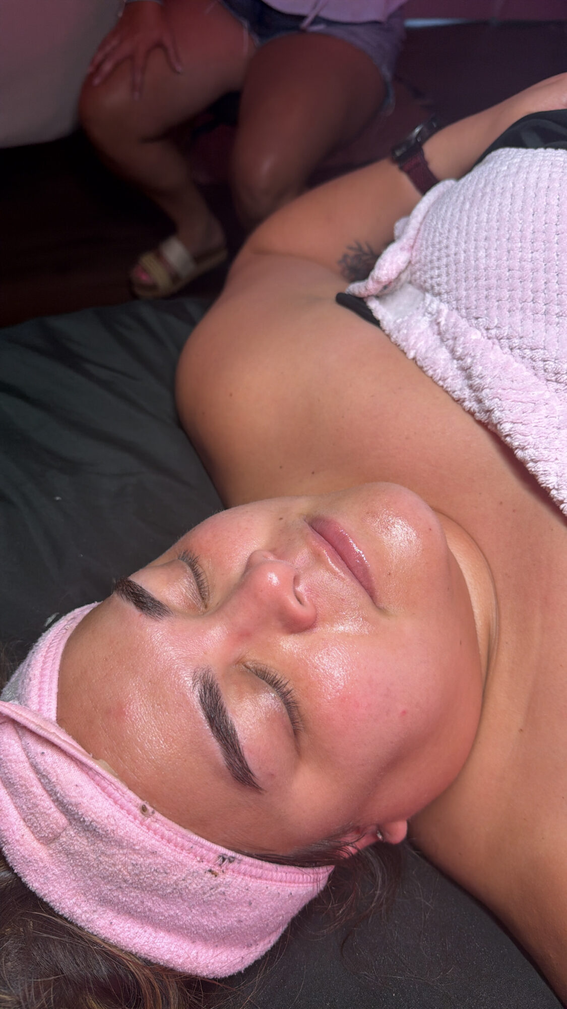 Woman lying down with eyes closed, wearing a pink headband and a white textured top.