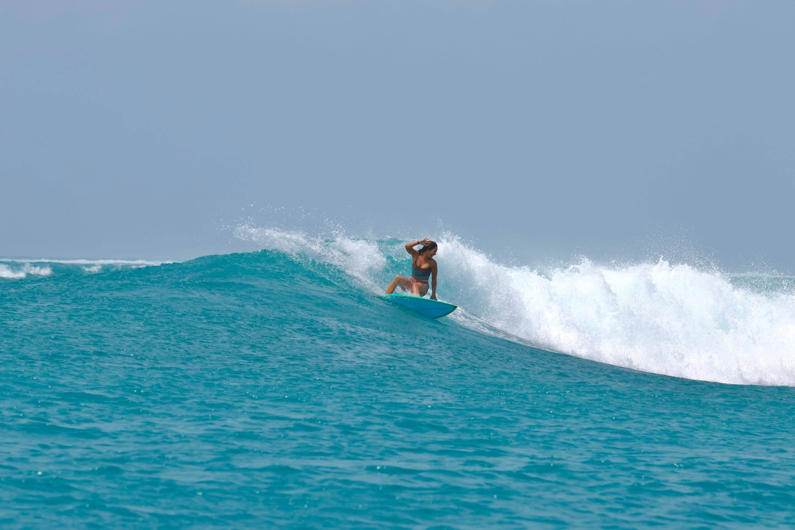 Person surfing on a wave in the ocean under a cloudy sky