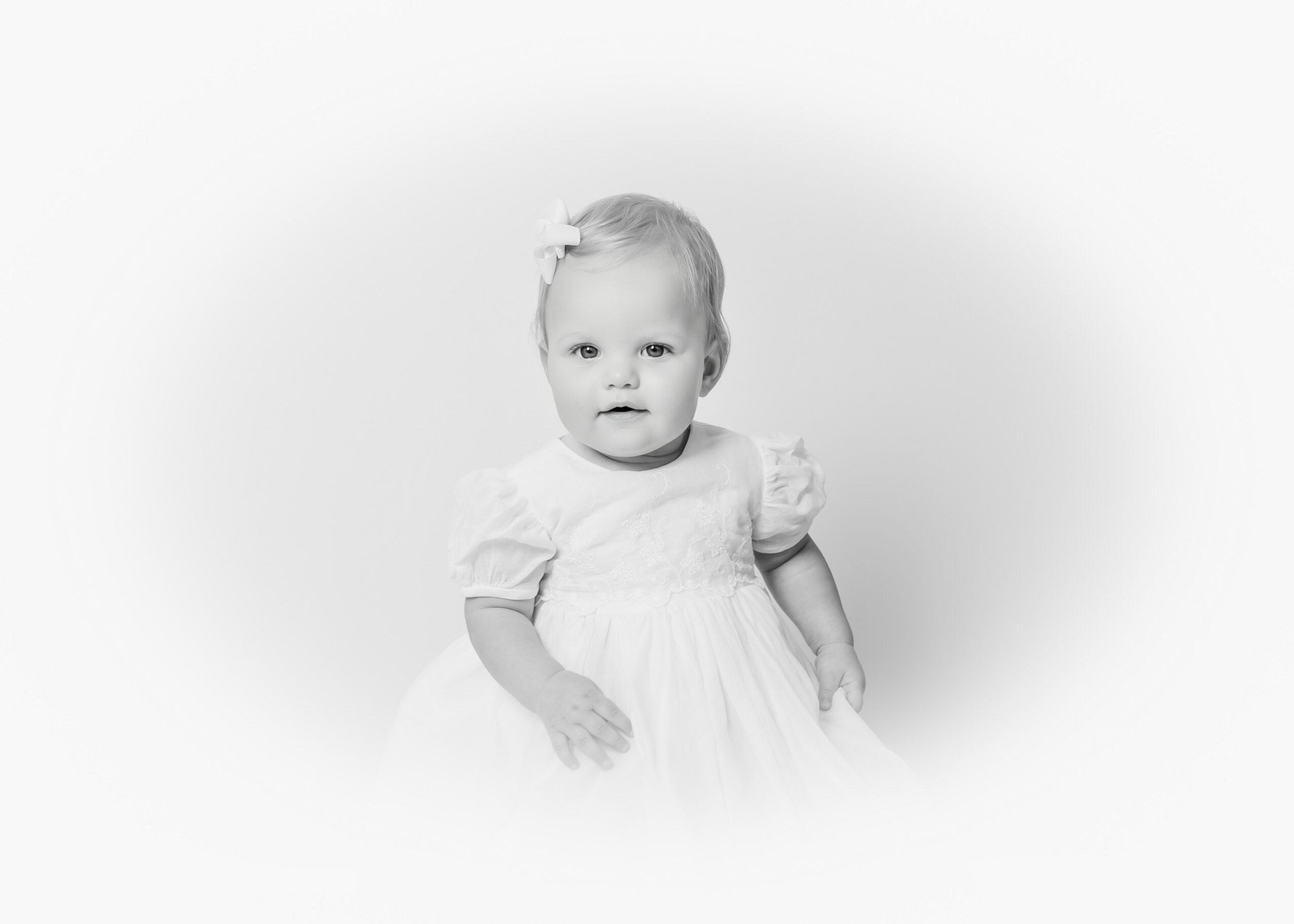Young girl in a white dress with puffed sleeves, standing against a plain background.