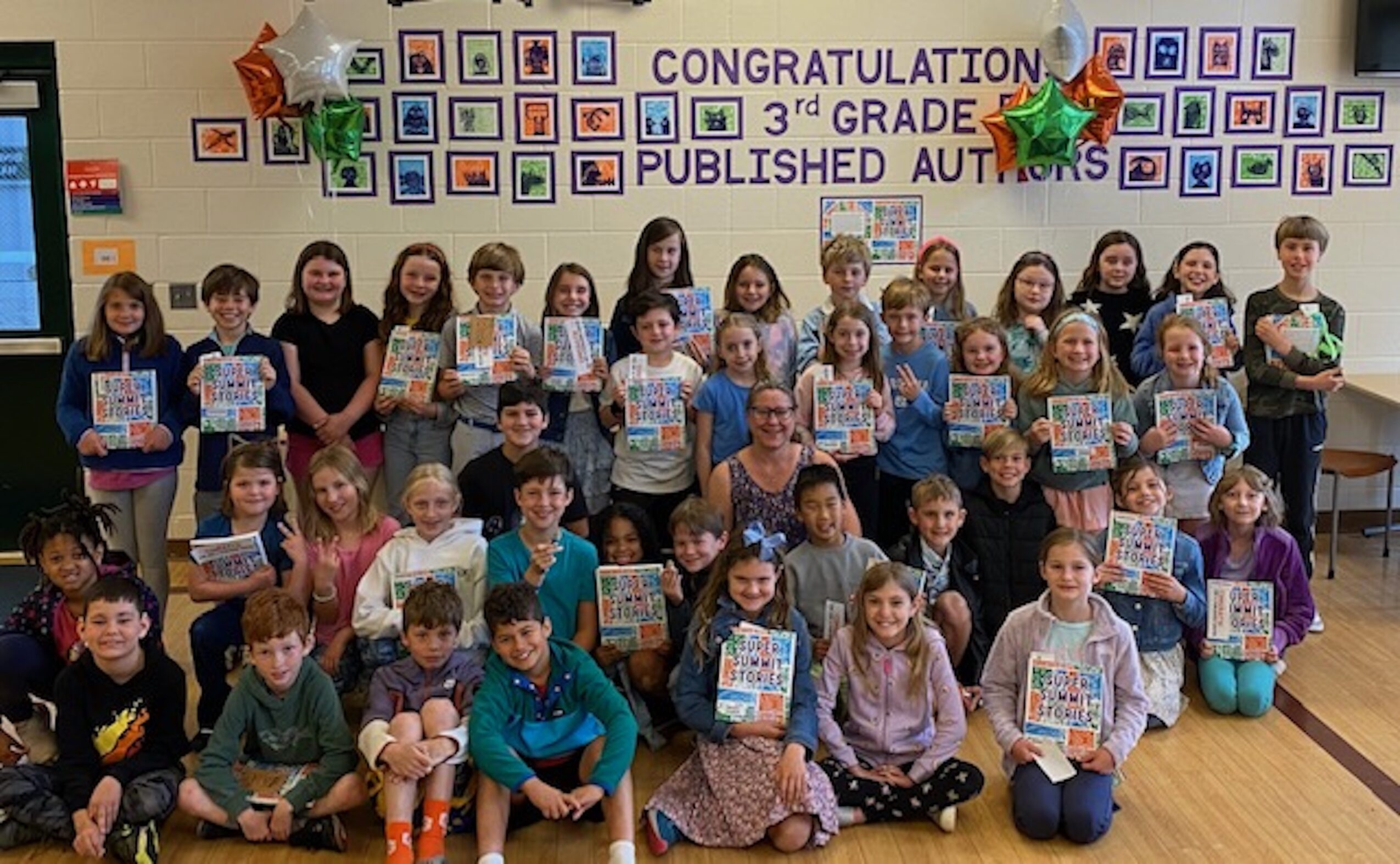 Group of children holding certificates in classroom with colorful decorations and a congratulatory banner.